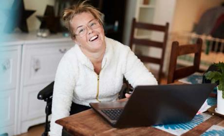 Getty 904516174 (Maskot) Portrait of smiling disabled woman using laptop at table in house