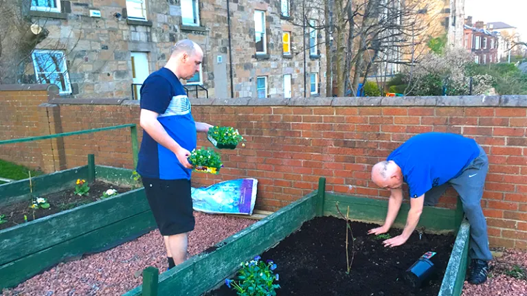 Two men planting out a raised bed in a garden