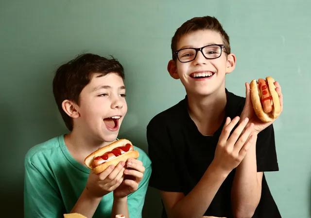 2 boys looking very happy to have hot dogs